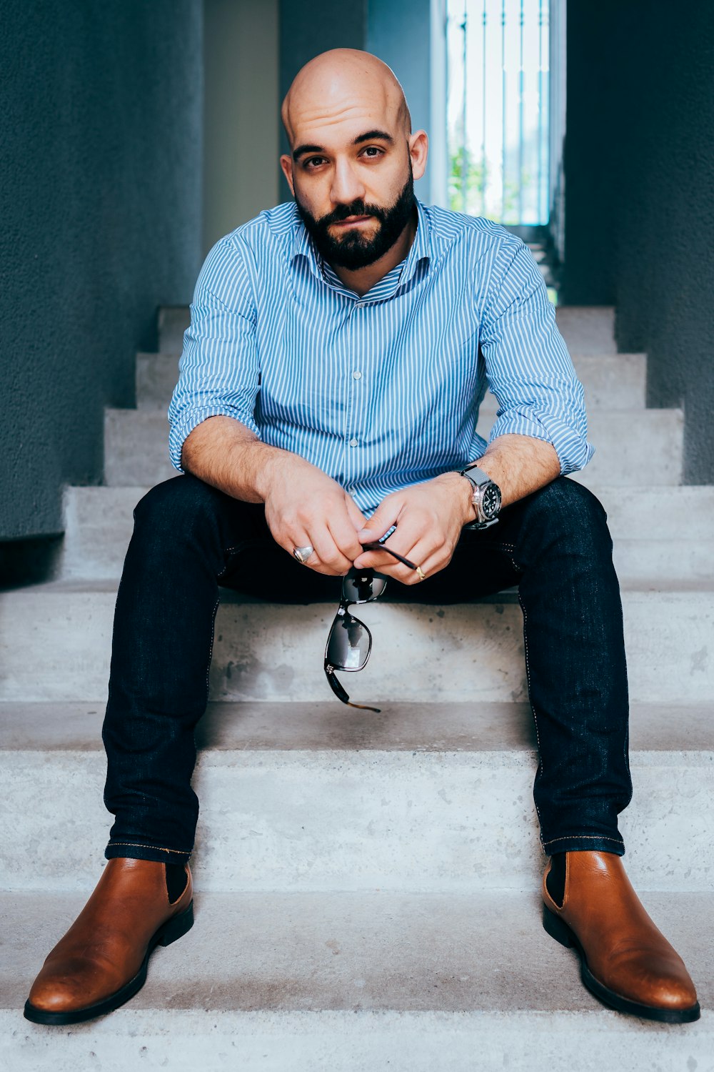 man in blue and white checkered dress shirt and black denim jeans sitting on concrete bench