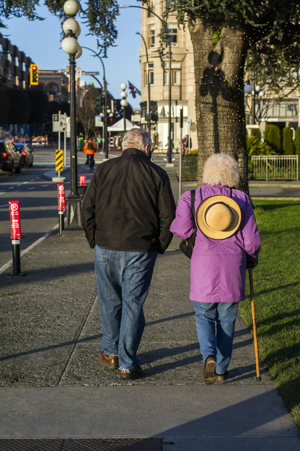 man in brown jacket and blue denim jeans standing on sidewalk during daytime