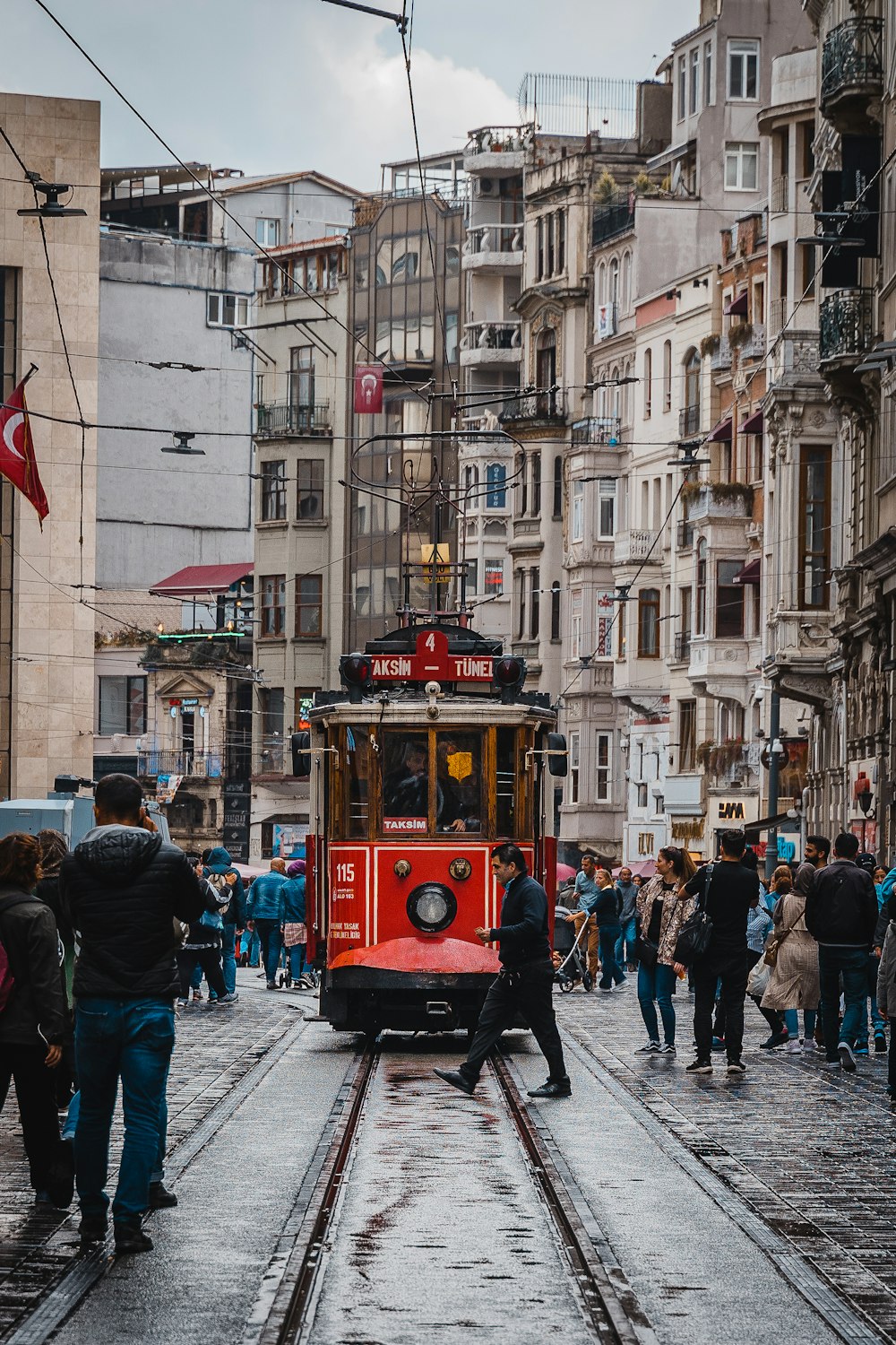 people walking on street near red tram during daytime