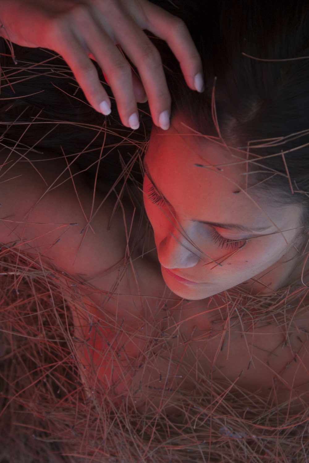 Femme avec du rouge à lèvres rouge allongée sur de l’herbe brune