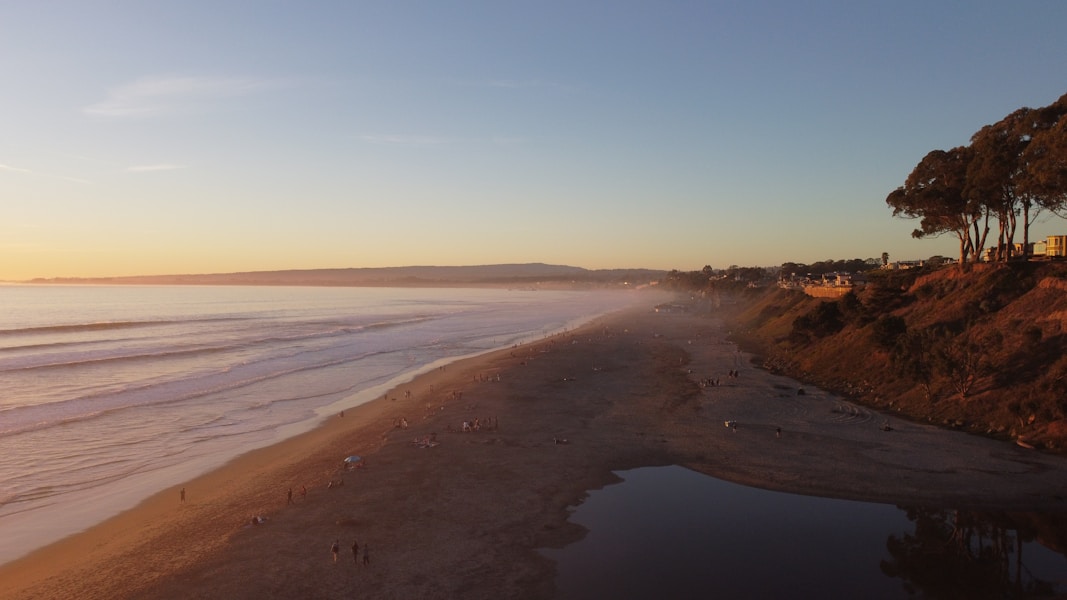 A serene coastal desert landscape at sunset with a small group exploring the shore.