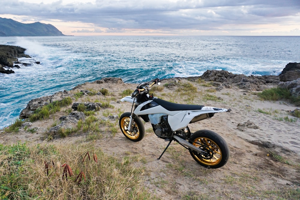 black motorcycle parked on green grass near body of water during daytime