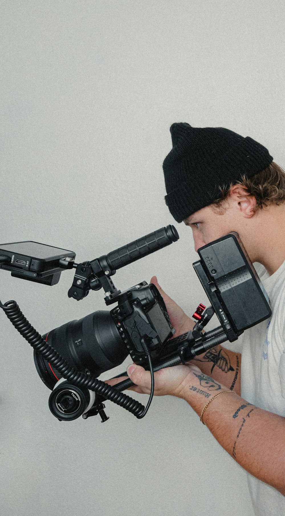 man in black knit cap holding black video camera