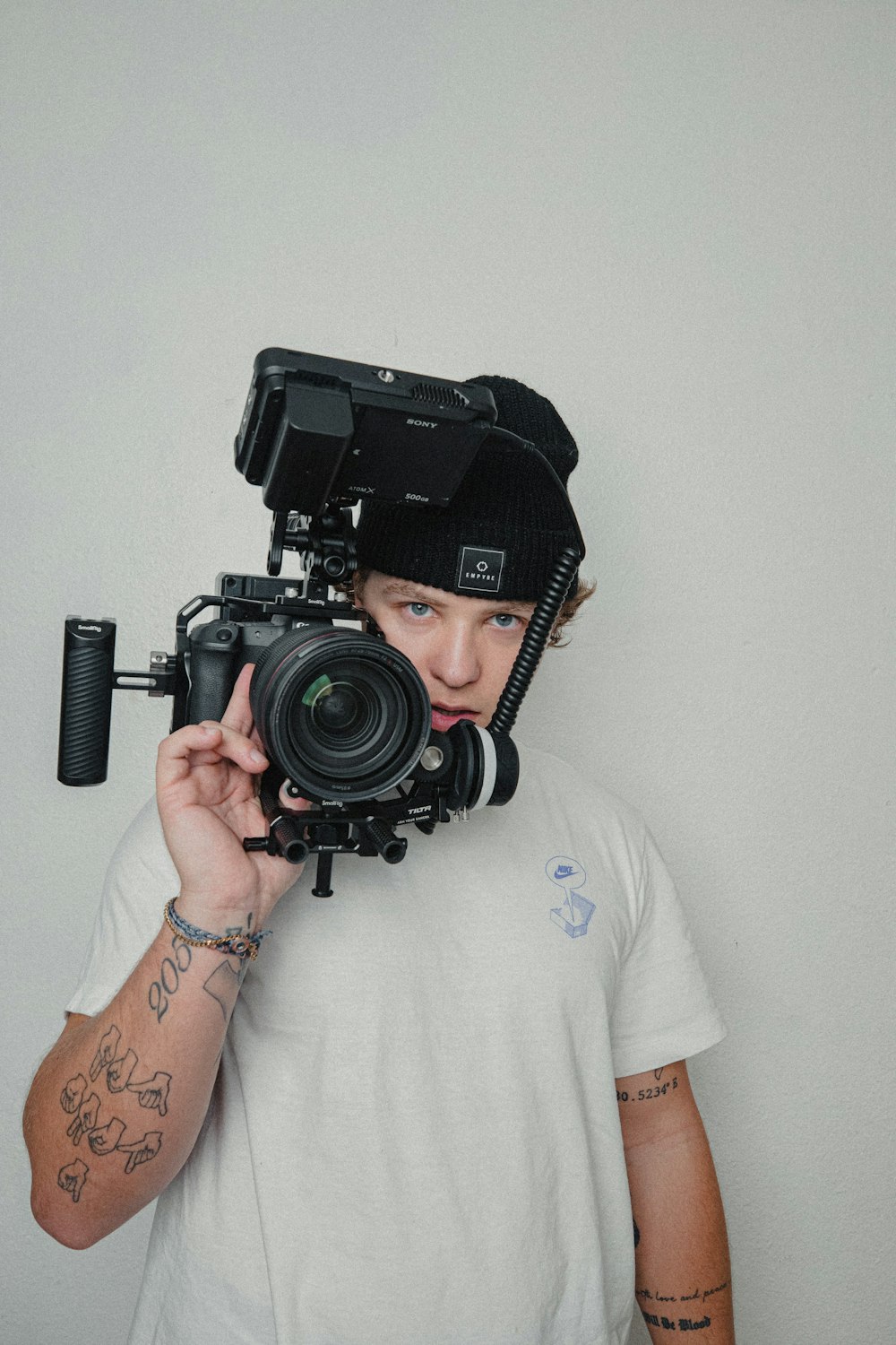 man in white t-shirt holding black nikon dslr camera