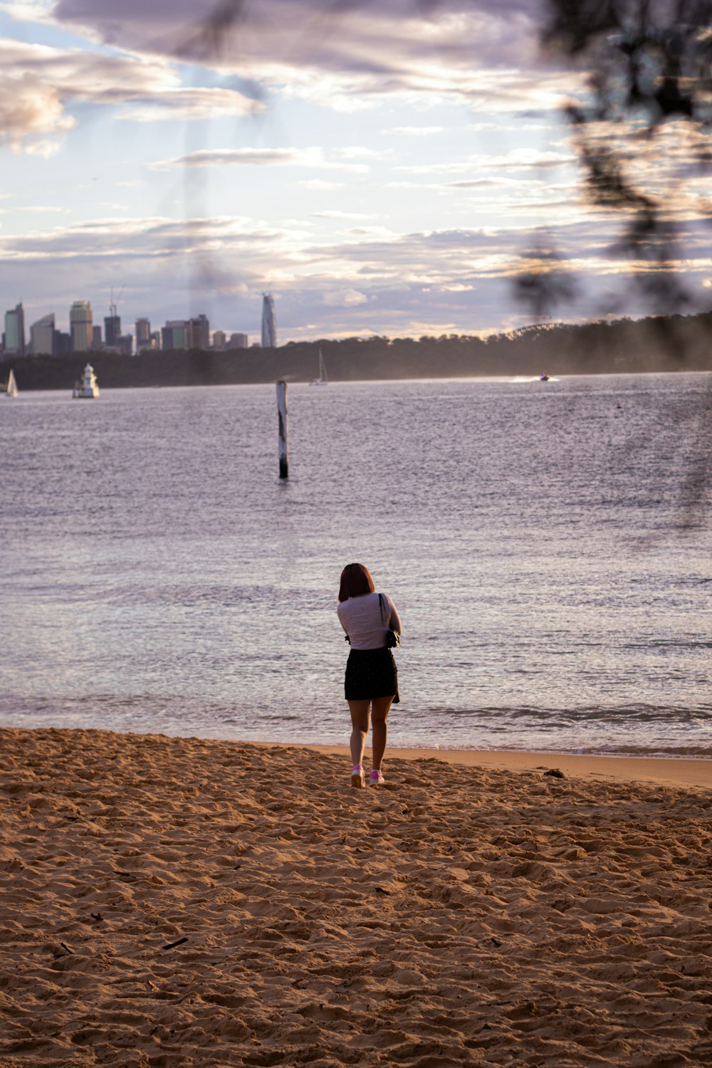 man in black t-shirt and black shorts standing on brown sand near body of water