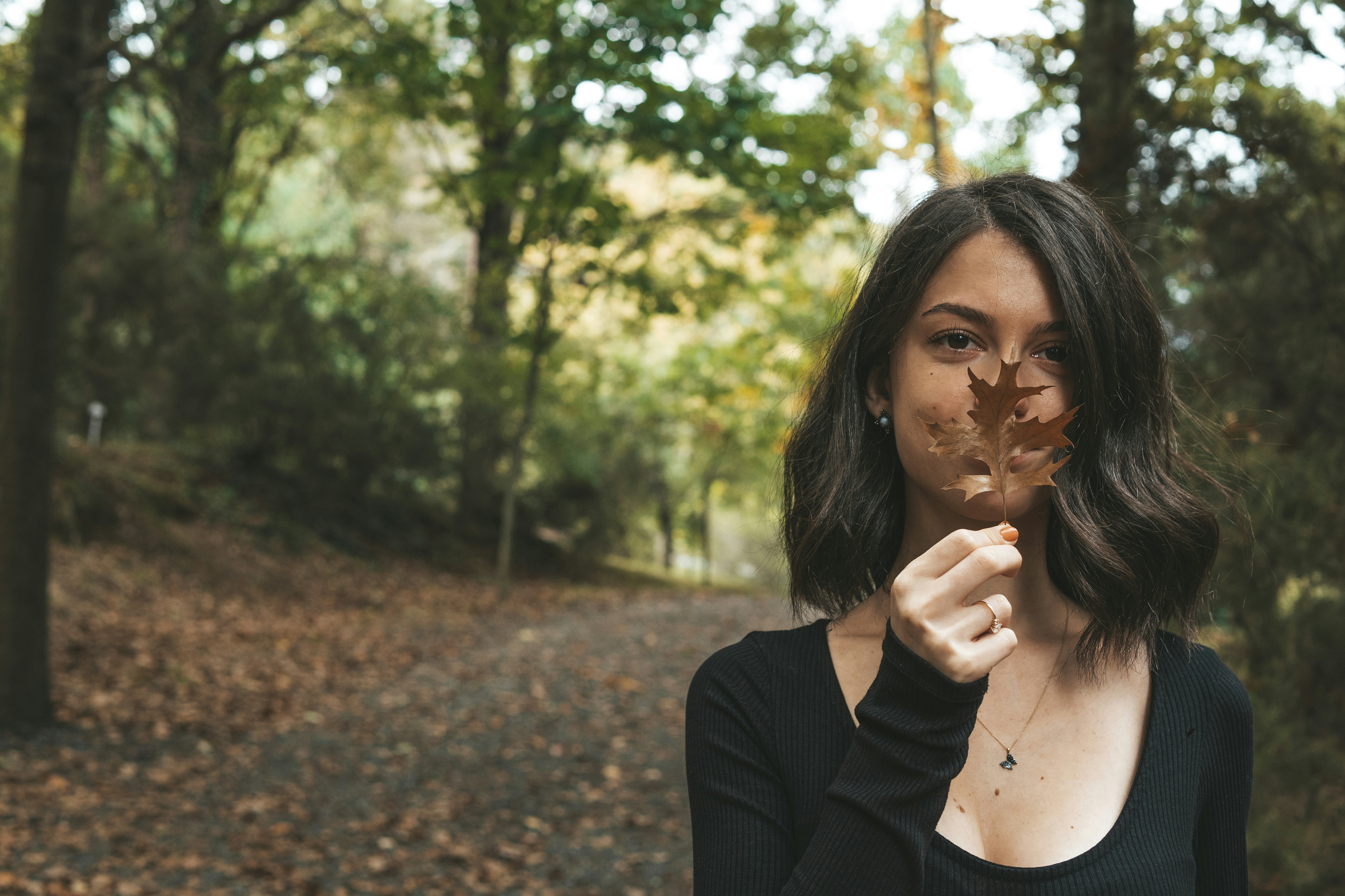 woman in black long sleeve shirt standing near green trees during daytime