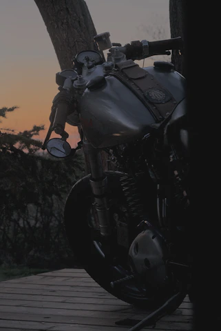 A sleek, rare vintage motorcycle parked against a rustic Indian street backdrop at sunset.