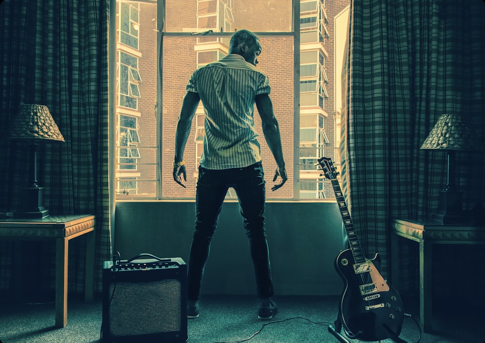 man in white t-shirt and black pants playing guitar