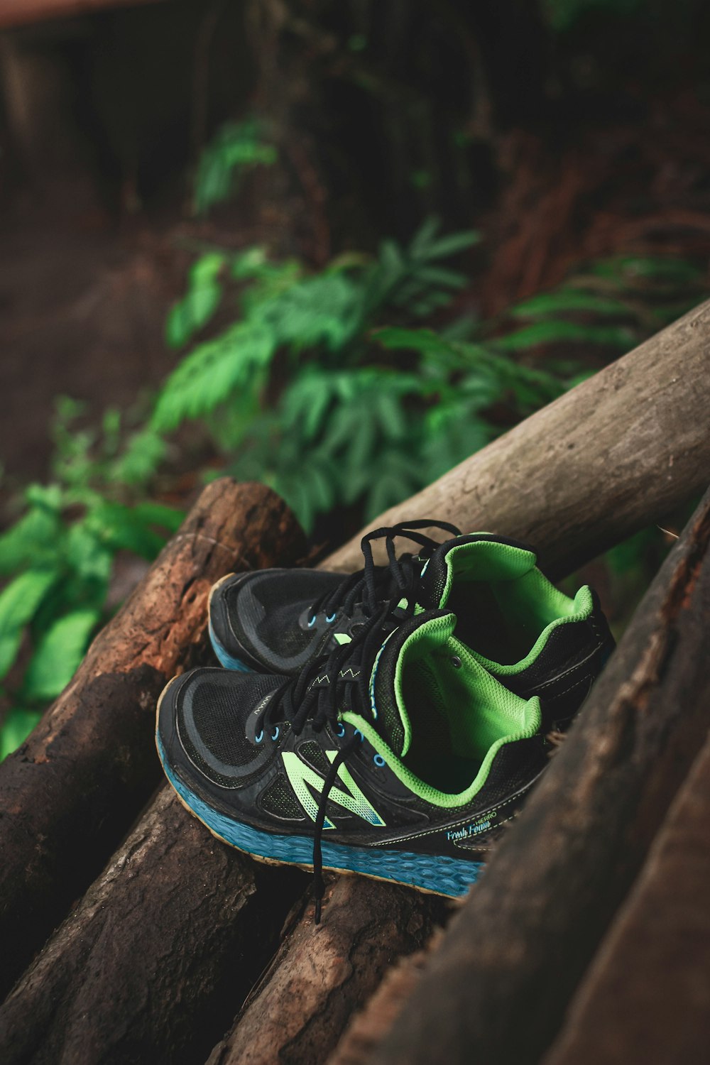 black and green nike athletic shoes on brown wooden log