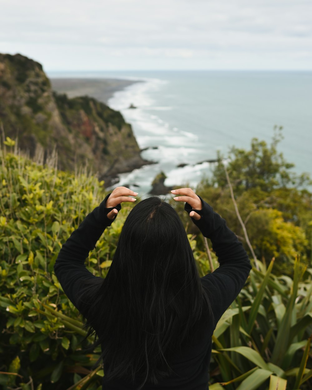 woman in black long sleeve shirt standing on green grass field near body of water during