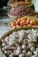 Bundles of dried shallots and garlic neatly stacked in traditional woven baskets.
