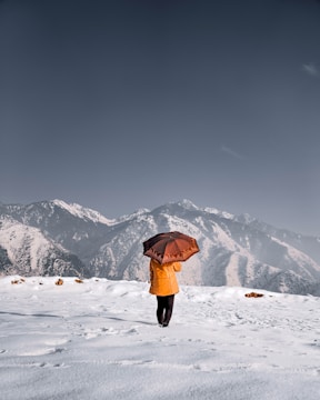 person in black jacket and black pants standing on snow covered ground during daytime