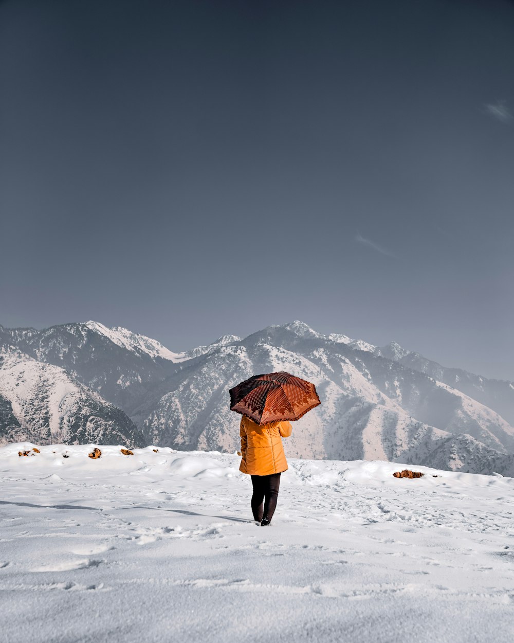 person in black jacket and black pants standing on snow covered ground during daytime