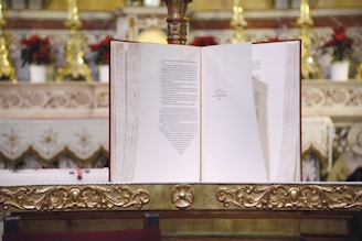 A beautifully decorated missal open on the altar, showing Latin prayers and ornate script.