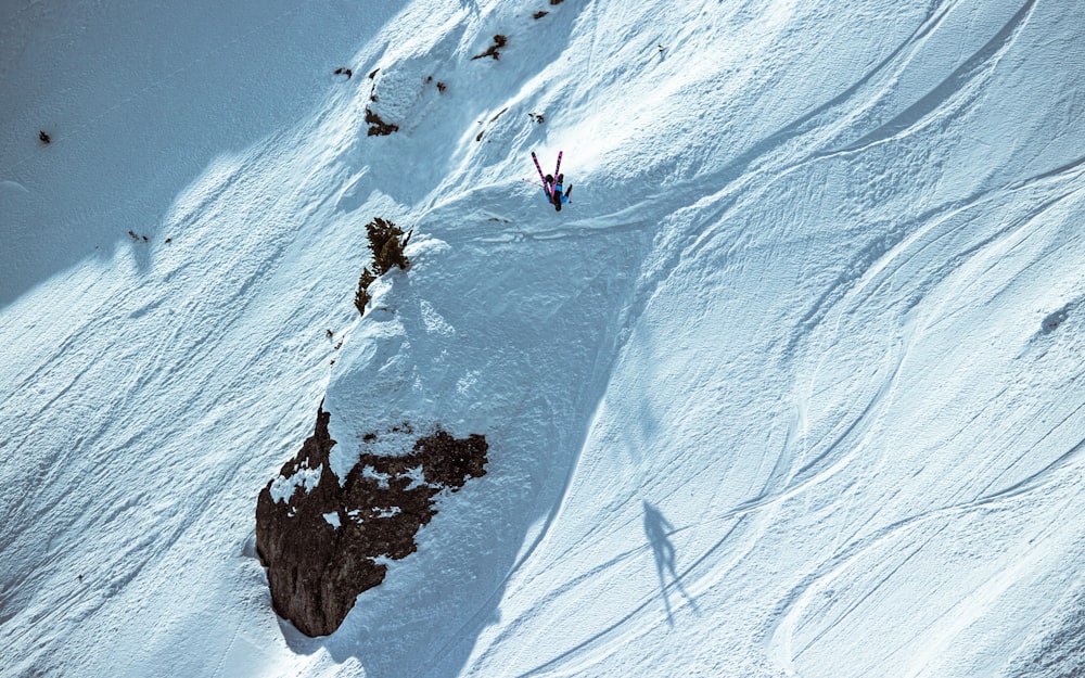 person in black jacket and black pants on snow covered mountain during daytime