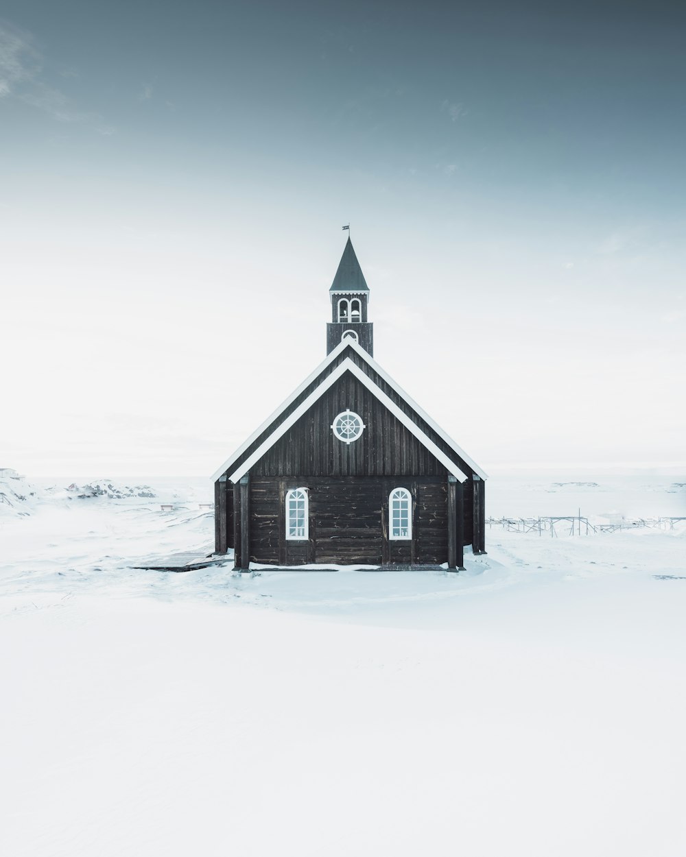 casa de madera negra en suelo cubierto de nieve bajo el cielo gris