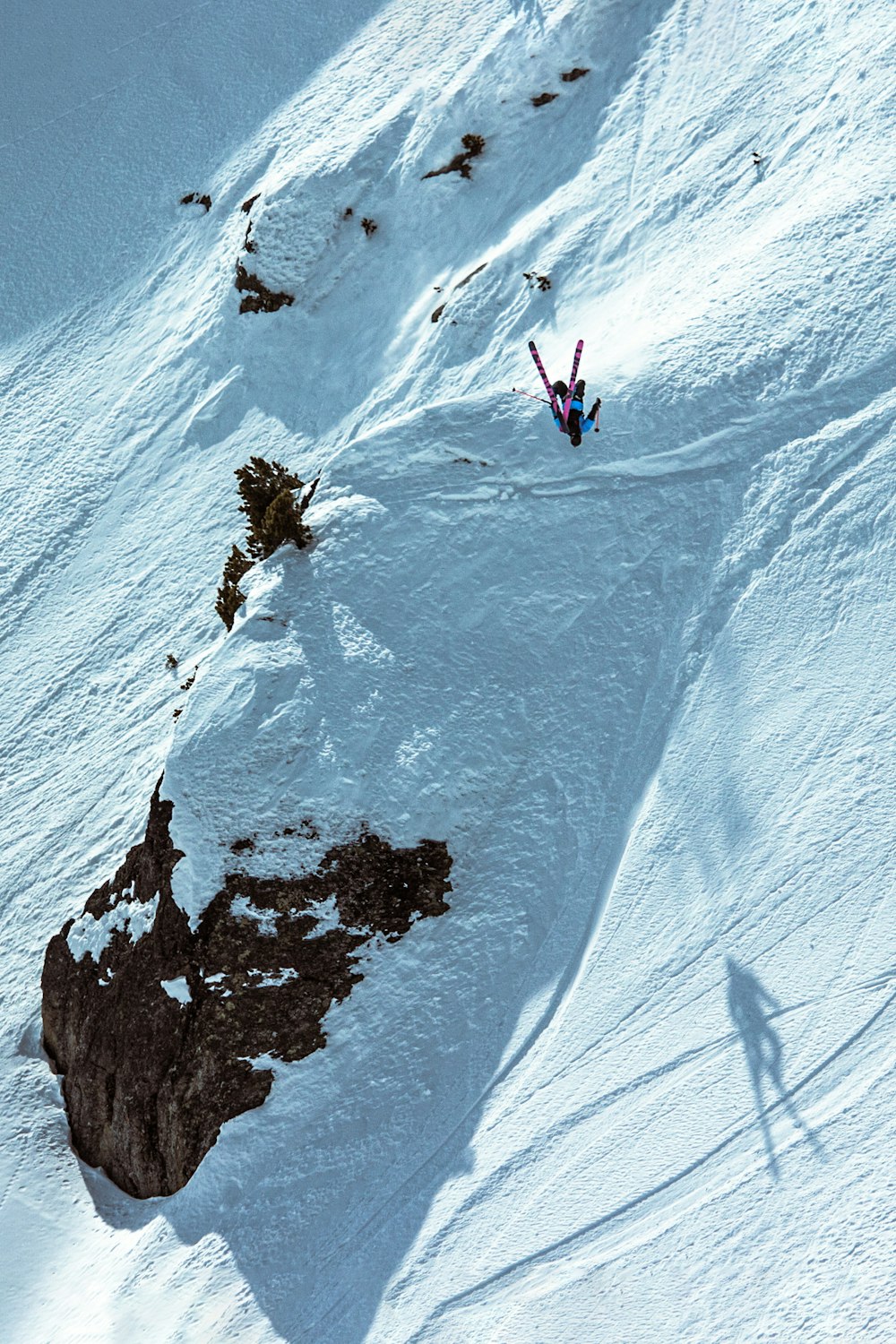 Person in schwarzer Jacke und blauer Hose tagsüber auf schneebedecktem Berg