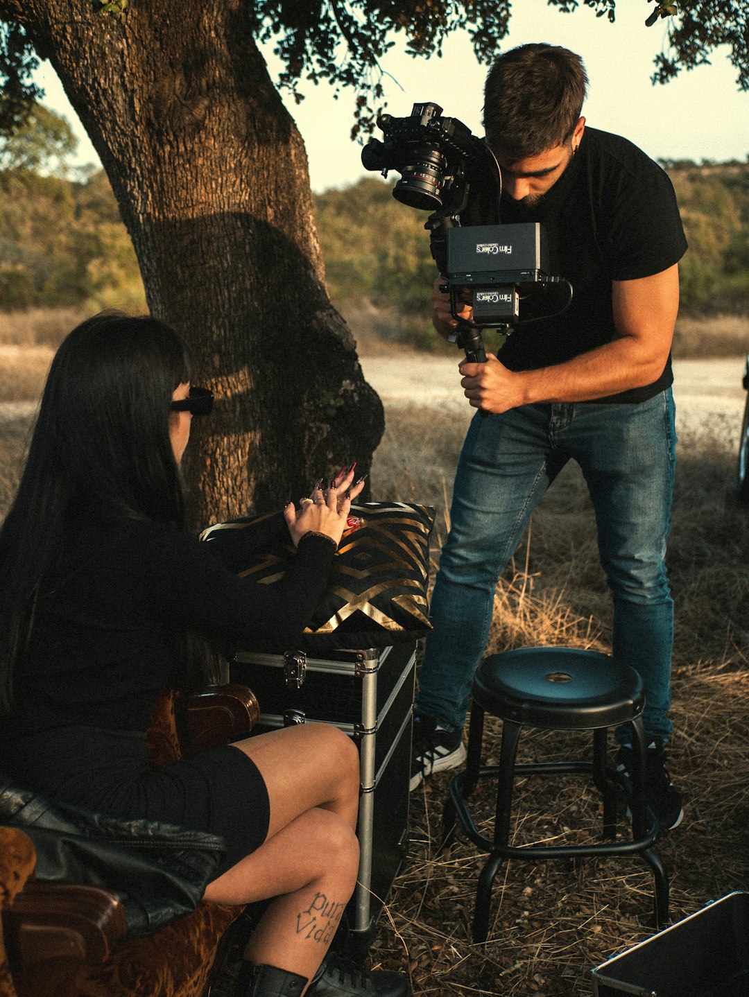 man and woman sitting on black metal chair holding black dslr camera