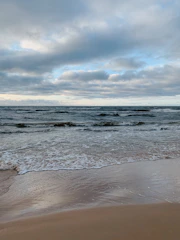ocean waves crashing on shore under cloudy sky during daytime
