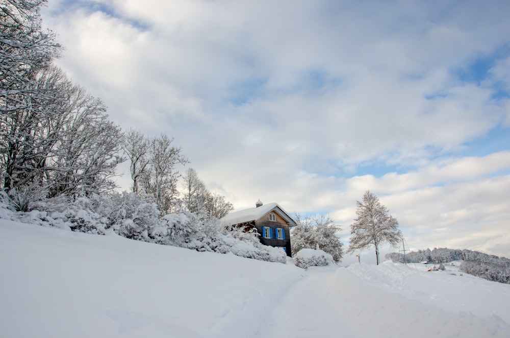 brown wooden house on snow covered ground under white clouds during daytime