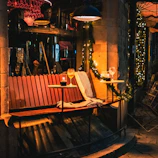 A cozy outdoor seating area featuring a rustic wooden bench with soft cushions under string lights at dusk.