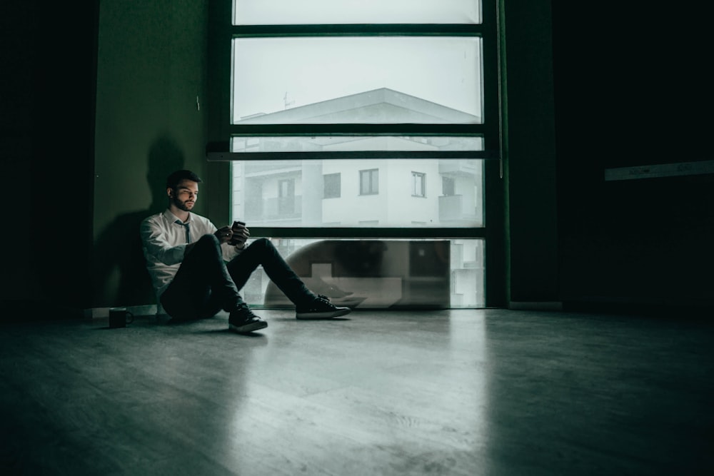 a man sitting on the floor looking at his cell phone