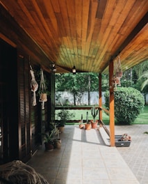 A cozy residential patio covered with a stylish lexan canopy surrounded by greenery