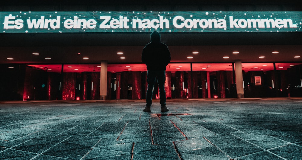 man in black jacket and pants walking on gray concrete floor