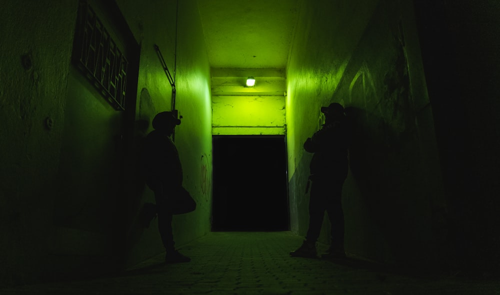 man in black jacket standing near green wall