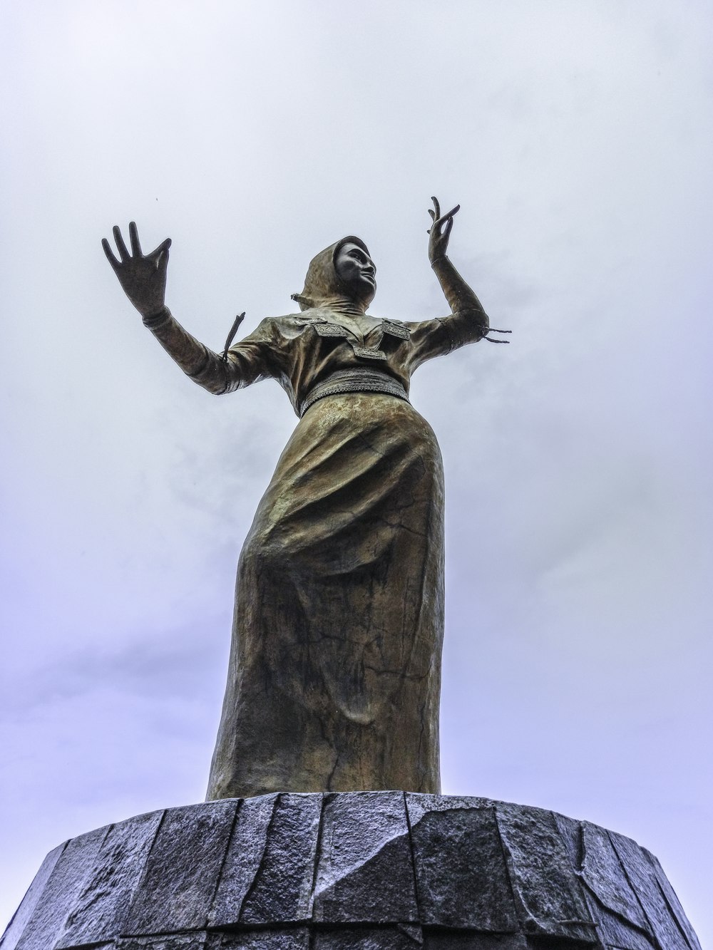 brown statue of man raising his right hand