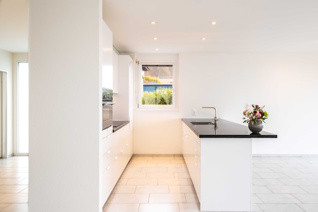 A sleek, sunlit kitchen featuring a polished quartz countertop with subtle gold veining and black accents.