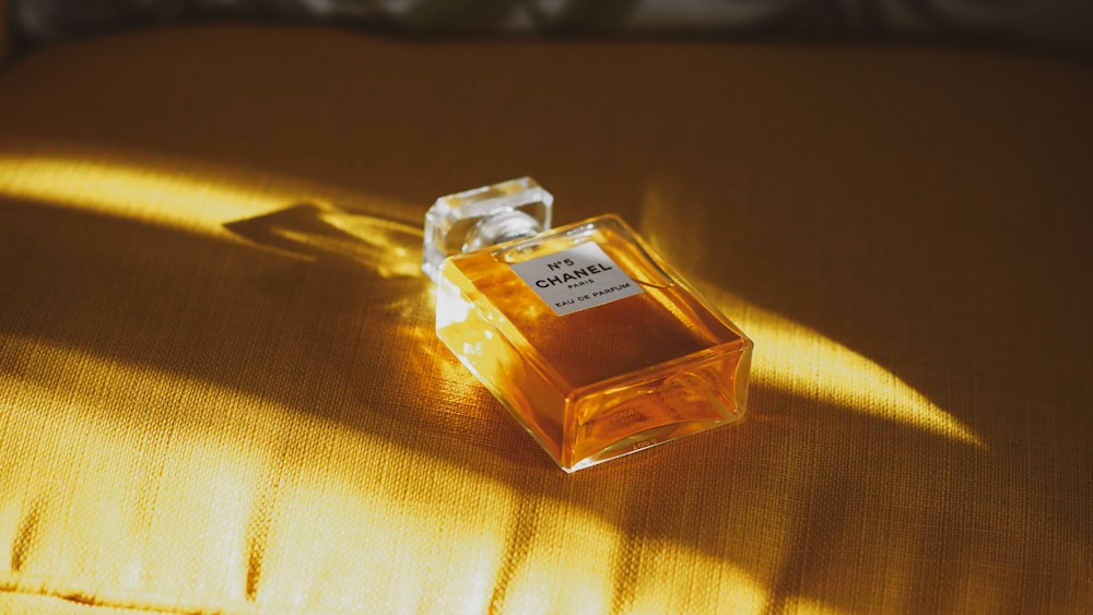 clear glass perfume bottle on brown textile