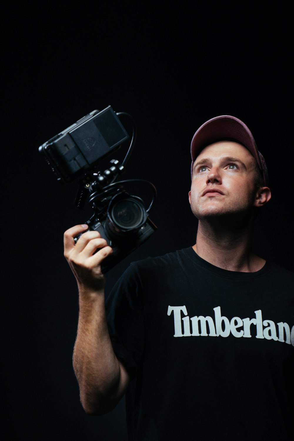 Hombre con camiseta negra de cuello redondo sosteniendo una cámara DSLR Nikon negra