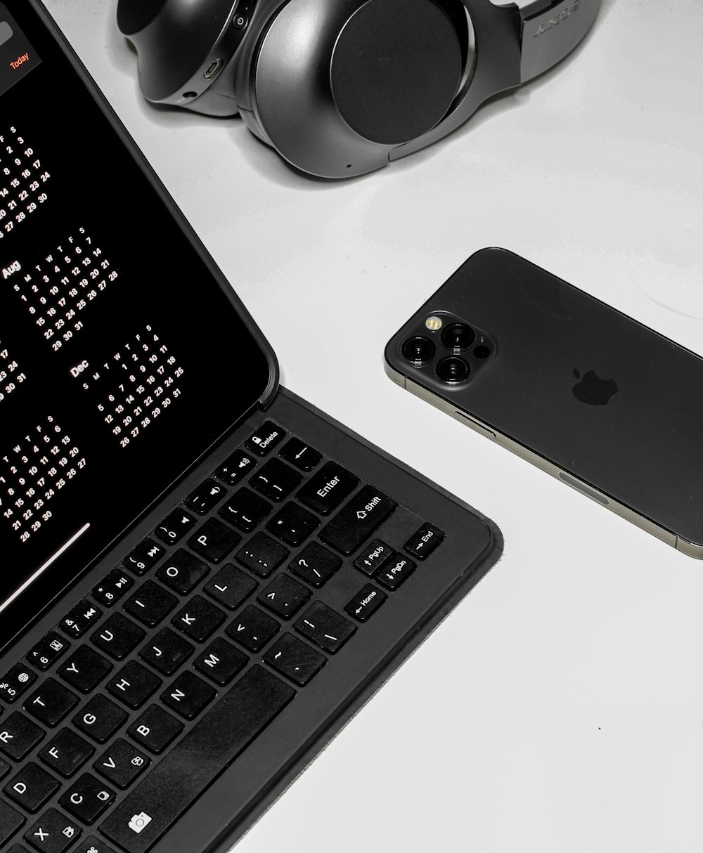 black ipad keyboard and black and white headphones