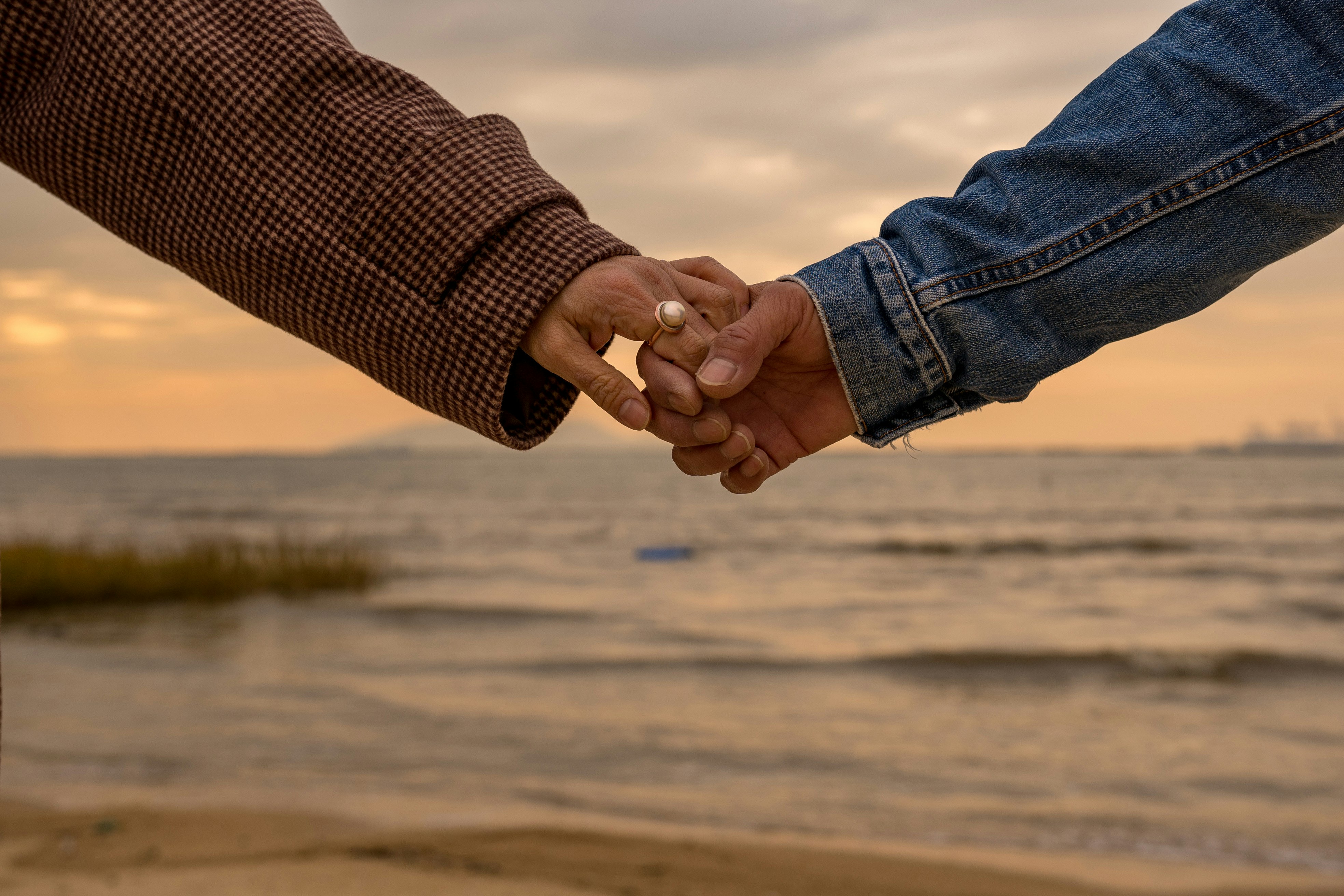 person in blue denim jeans and brown and white checked shirt holding hands with woman in near near on near