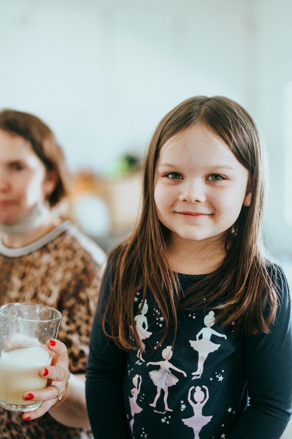 girl in black and white floral crew neck shirt holding clear drinking glass