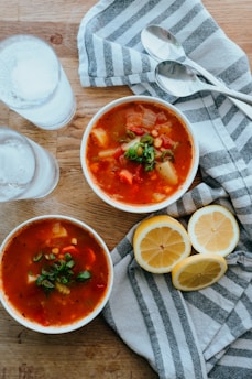 A steaming bowl of vegetable soup garnished with fresh herbs on a clean white plate.