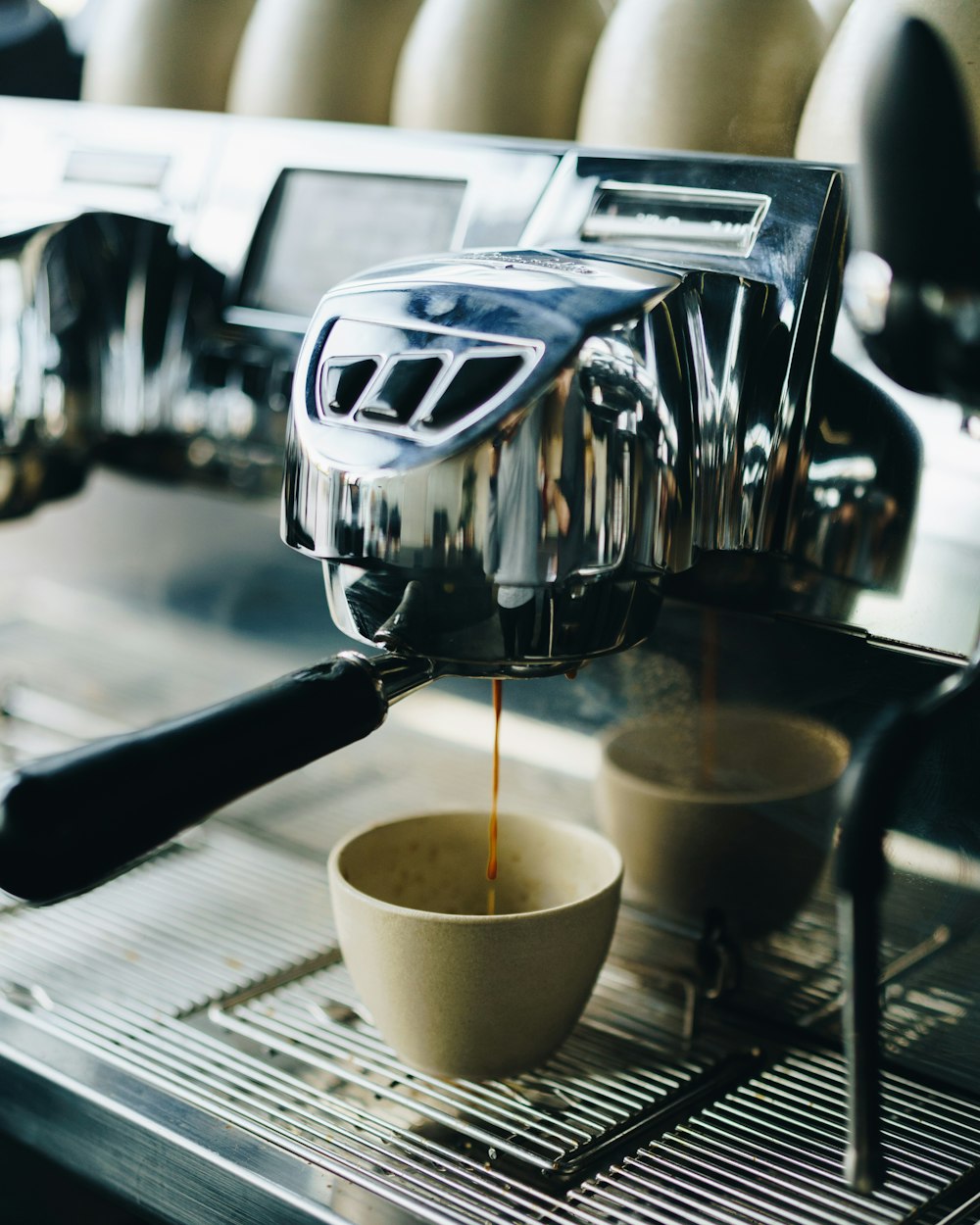 weiße Keramiktasse auf silberner Espressomaschine