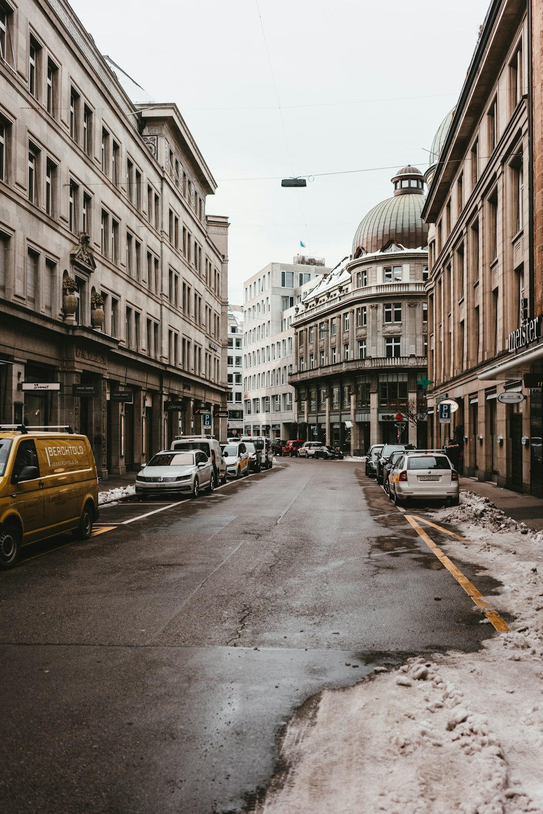 cars parked on side of the road near buildings during daytime