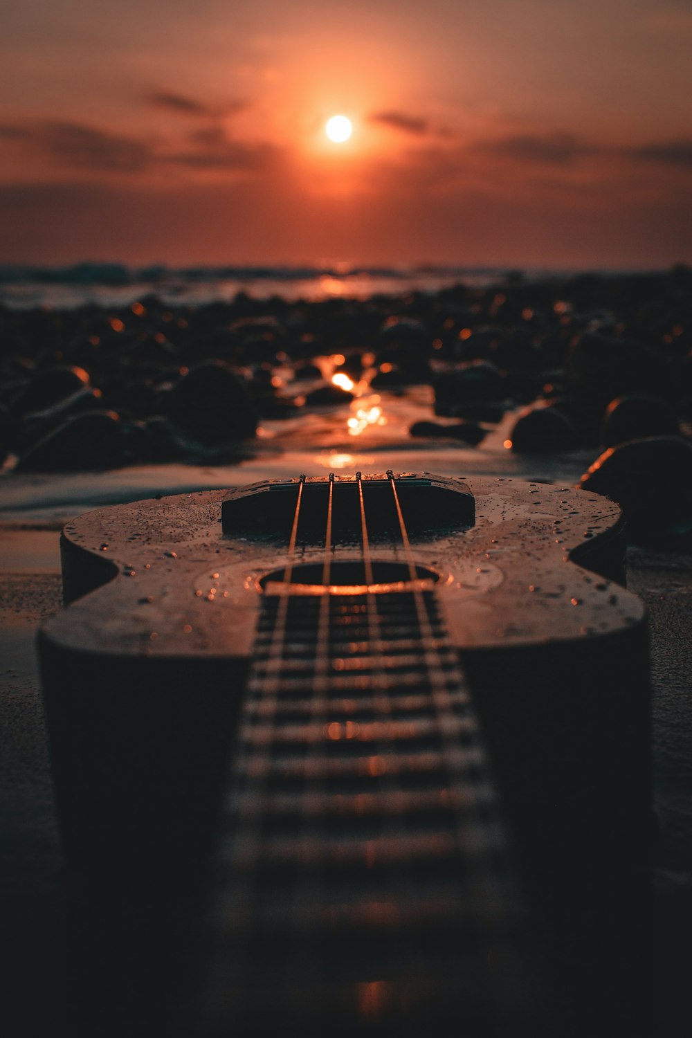 guitare acoustique brune sur rocher brun au coucher du soleil