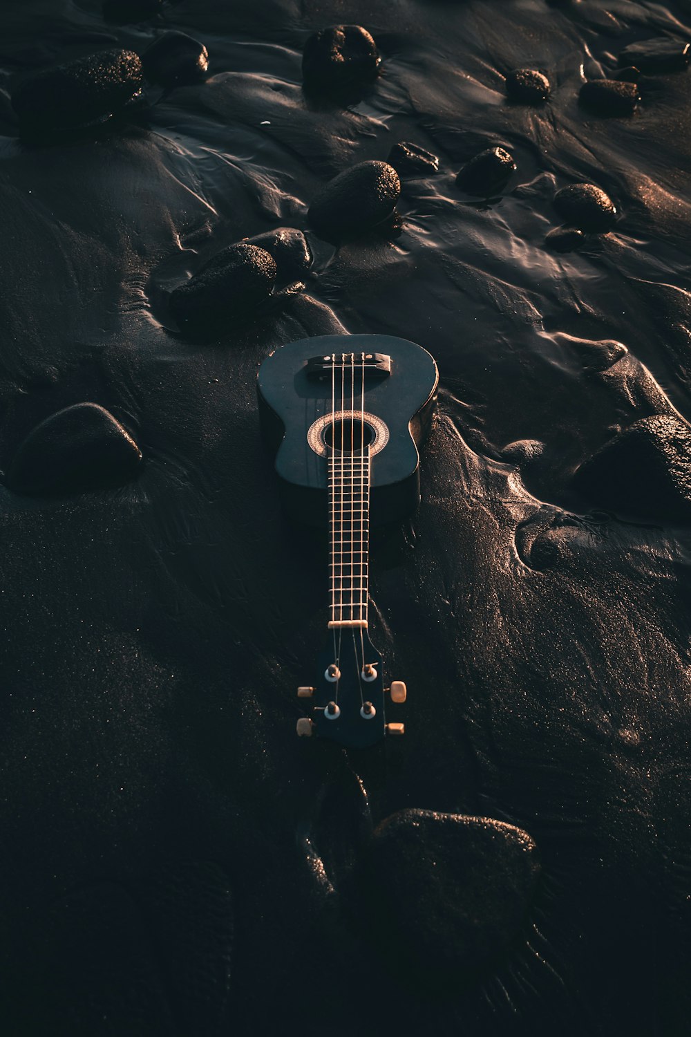 Guitarra eléctrica blanca y negra sobre arena negra