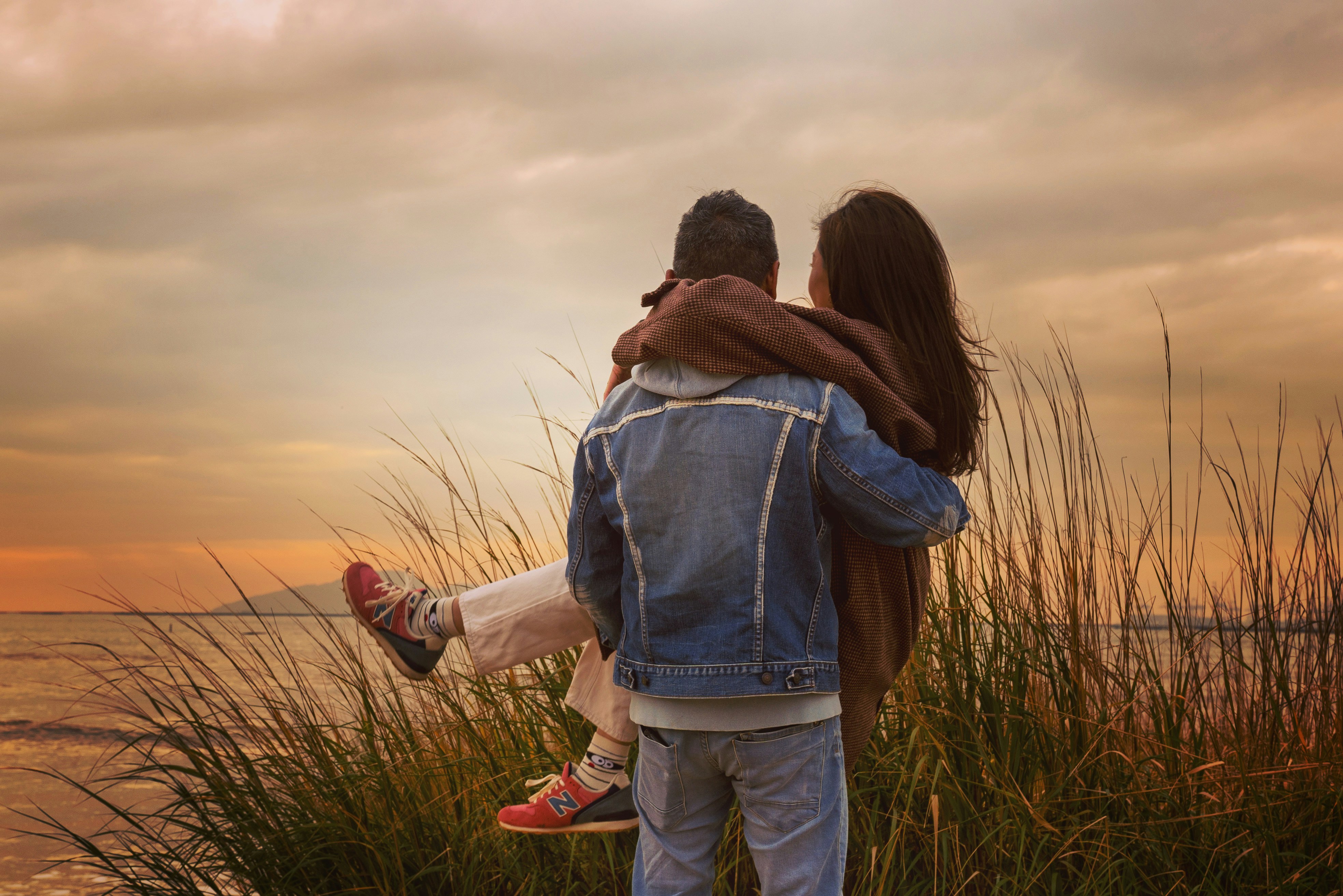 woman in blue denim jacket and blue denim jeans standing on green grass field during daytime