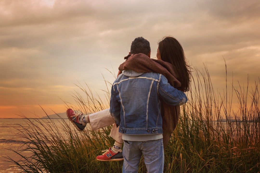 woman in blue denim jacket and blue denim jeans standing on green grass field during daytime