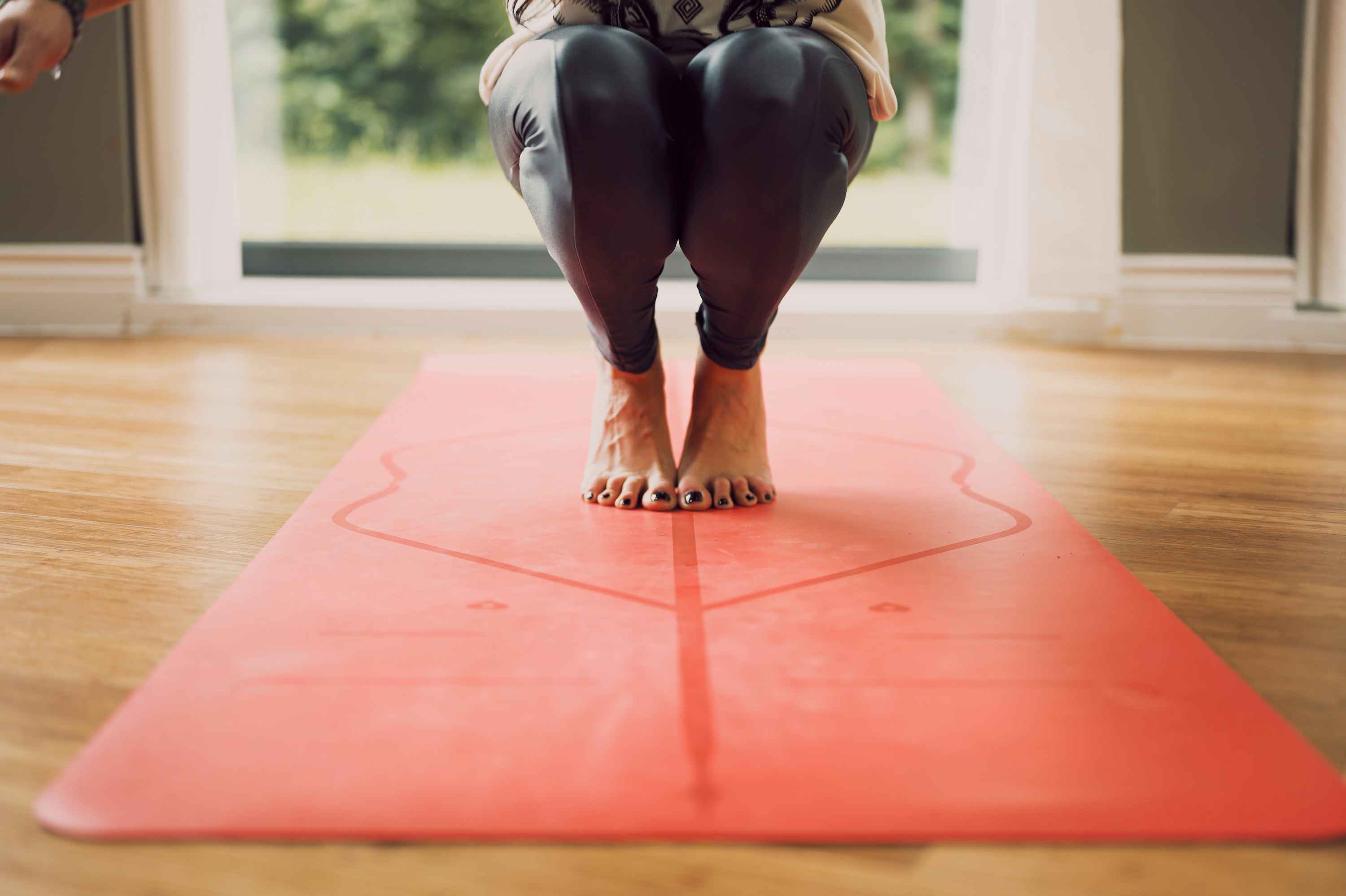 woman in black leggings and brown shoes sitting on red floor