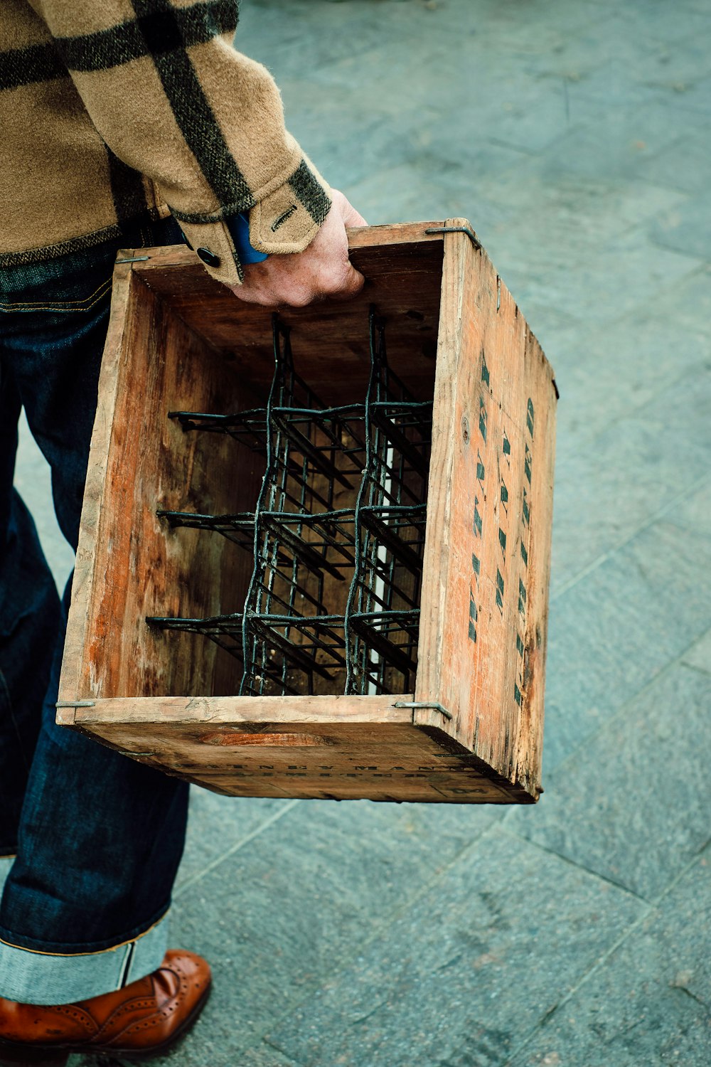 person in blue denim jeans holding brown wooden crate