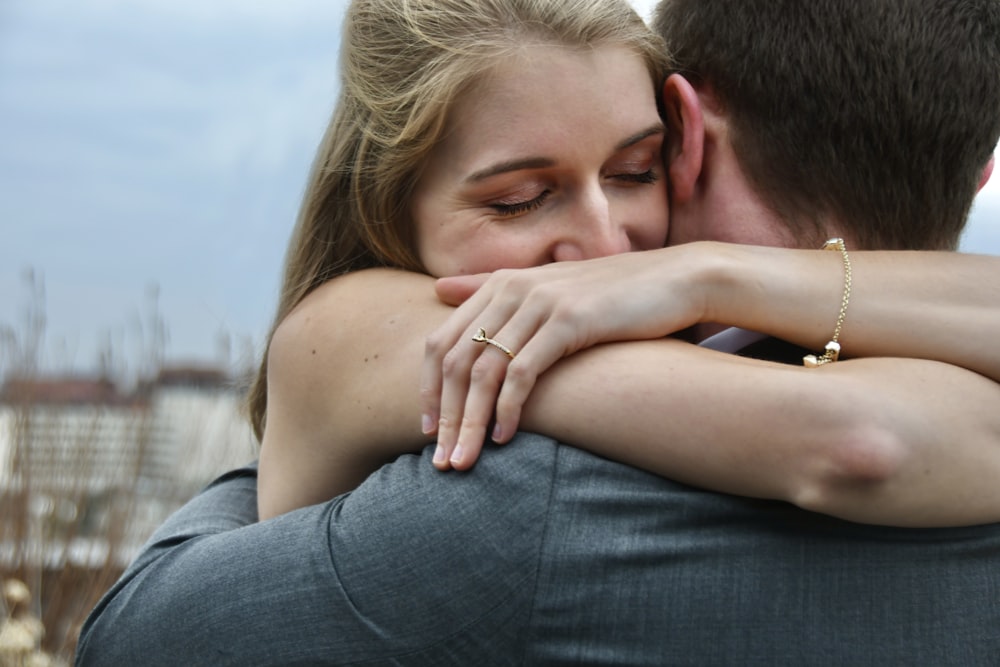 man in blue denim jeans kissing woman in white shirt