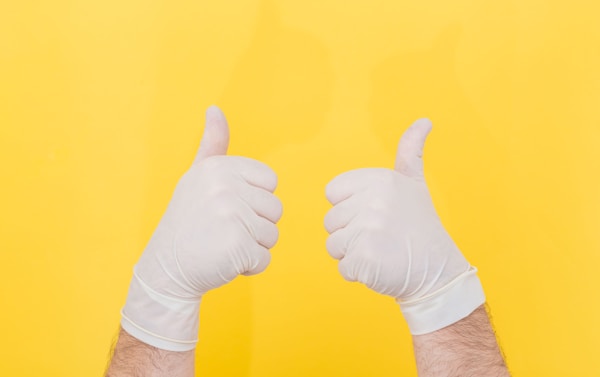 The close plan. Two hands in white medical gloves on a yellow background show thumbs up, like. The medicine. Place for an inscription. Advertising. All right. Like. Medical gloves.by Diana Polekhina