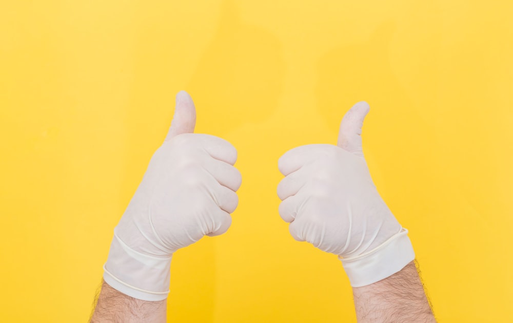 Persona con camisa blanca de manga larga haciendo el signo del pulgar hacia arriba