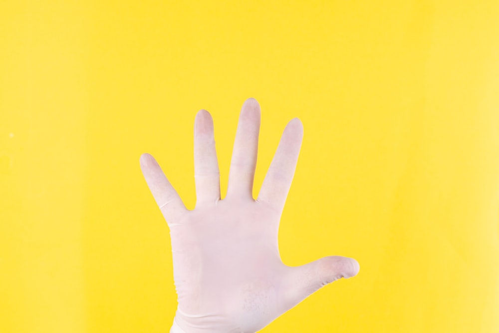 黄色の背景に人の左手