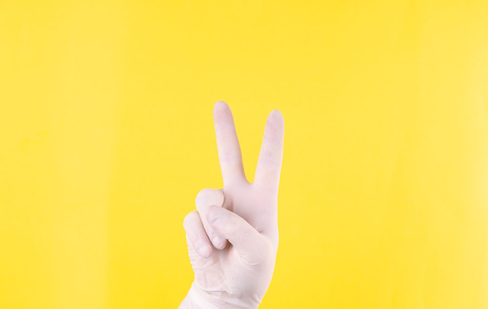 persons hand doing peace sign